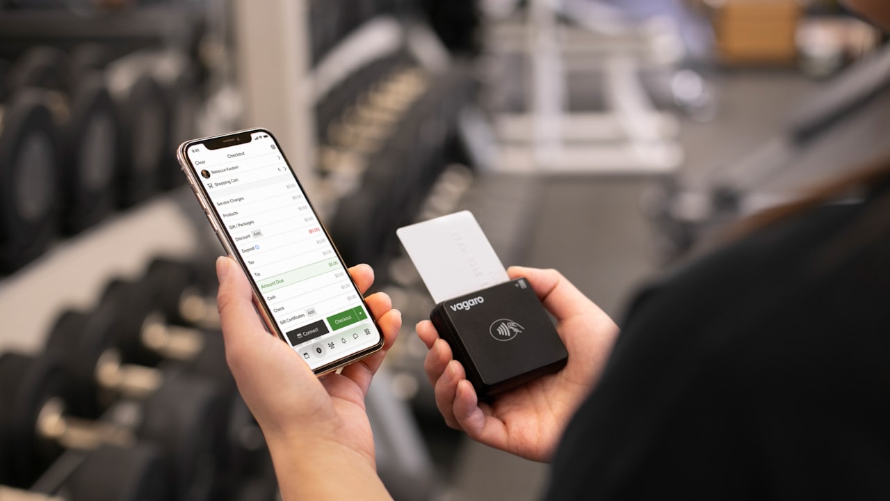 Person holding phone and payment device in gym