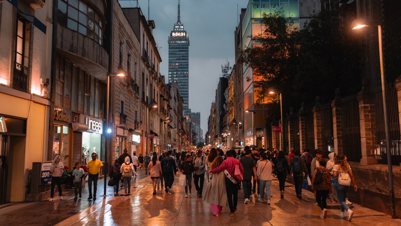 a group of people walking down a street next to tall buildings