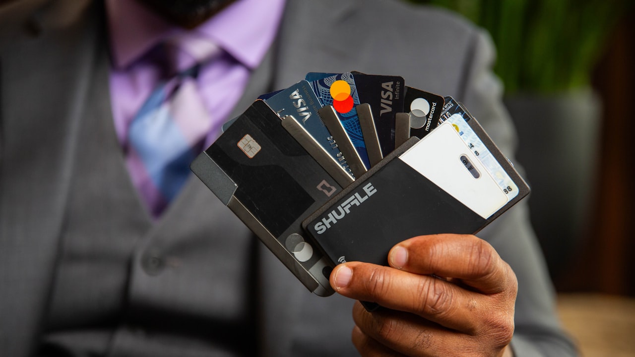 a man in a suit holding four credit cards
