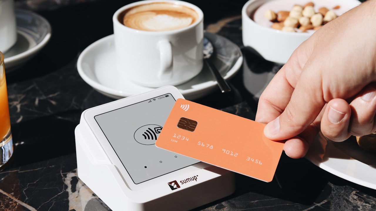 A person holding a credit card over a table