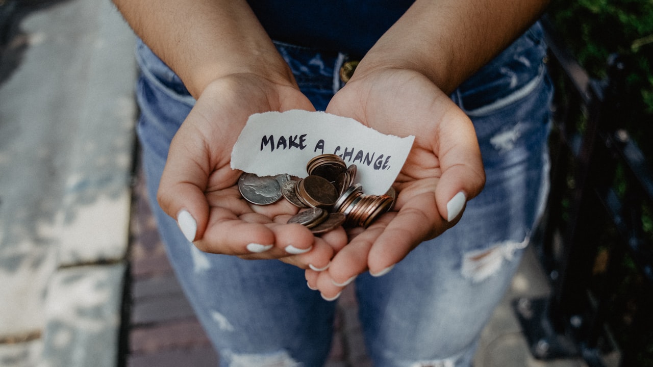 person showing both hands with make a change note and coins