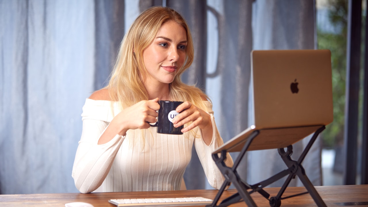 a woman sitting at a table with a laptop and a cup of coffee