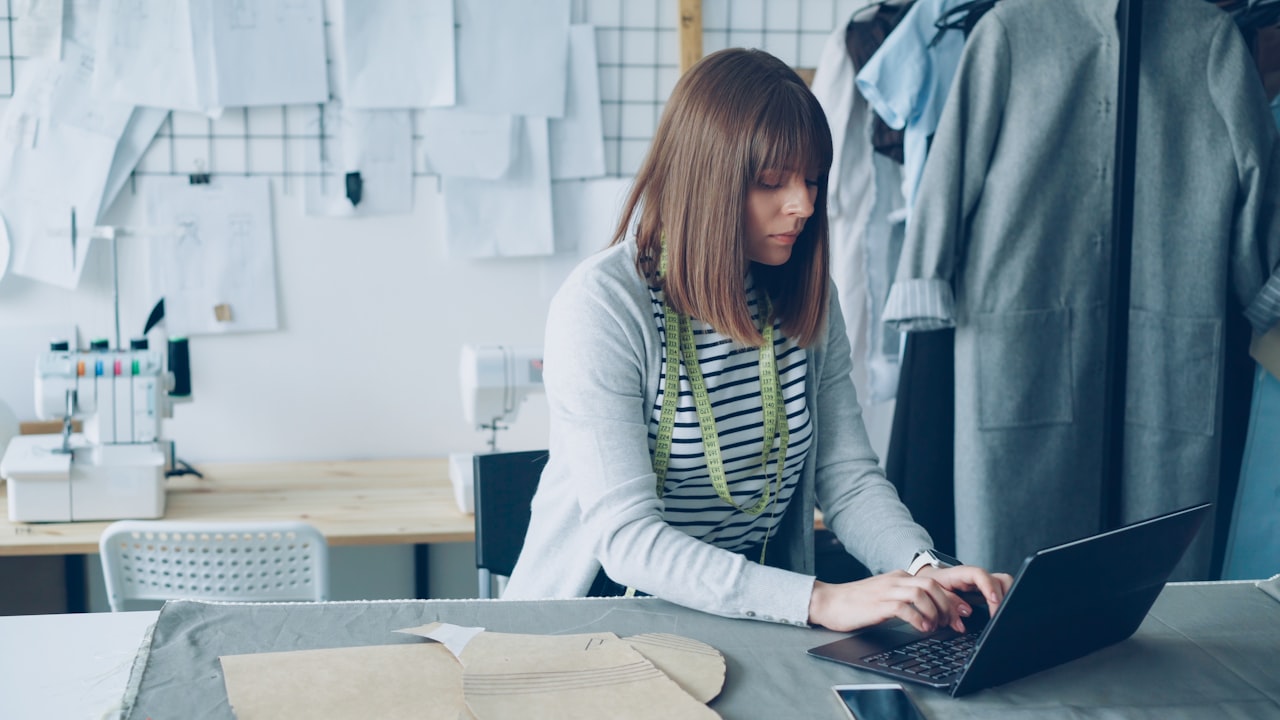 Fashion designer works on a laptop in her atelier.