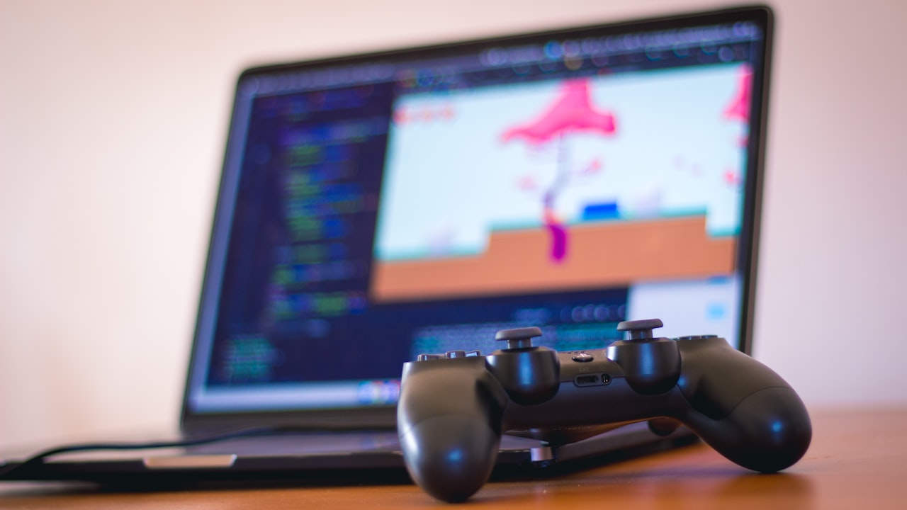black laptop computer beside controller on brown wooden surface