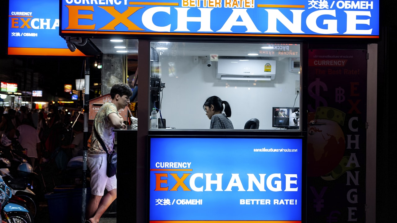 man in gray short standing near counter of currency exchange
