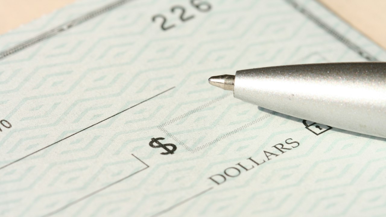 A pen rests on a check near the dollars line